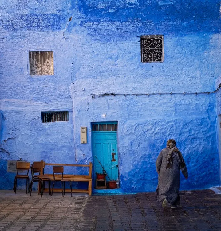 Woman walking towards a blue building wall