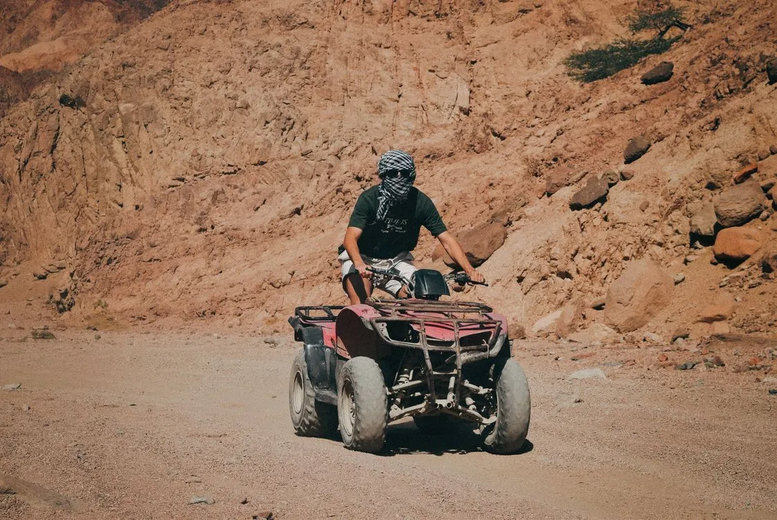 Tourists riding a red Quad Bike ATV in the Palmeraie